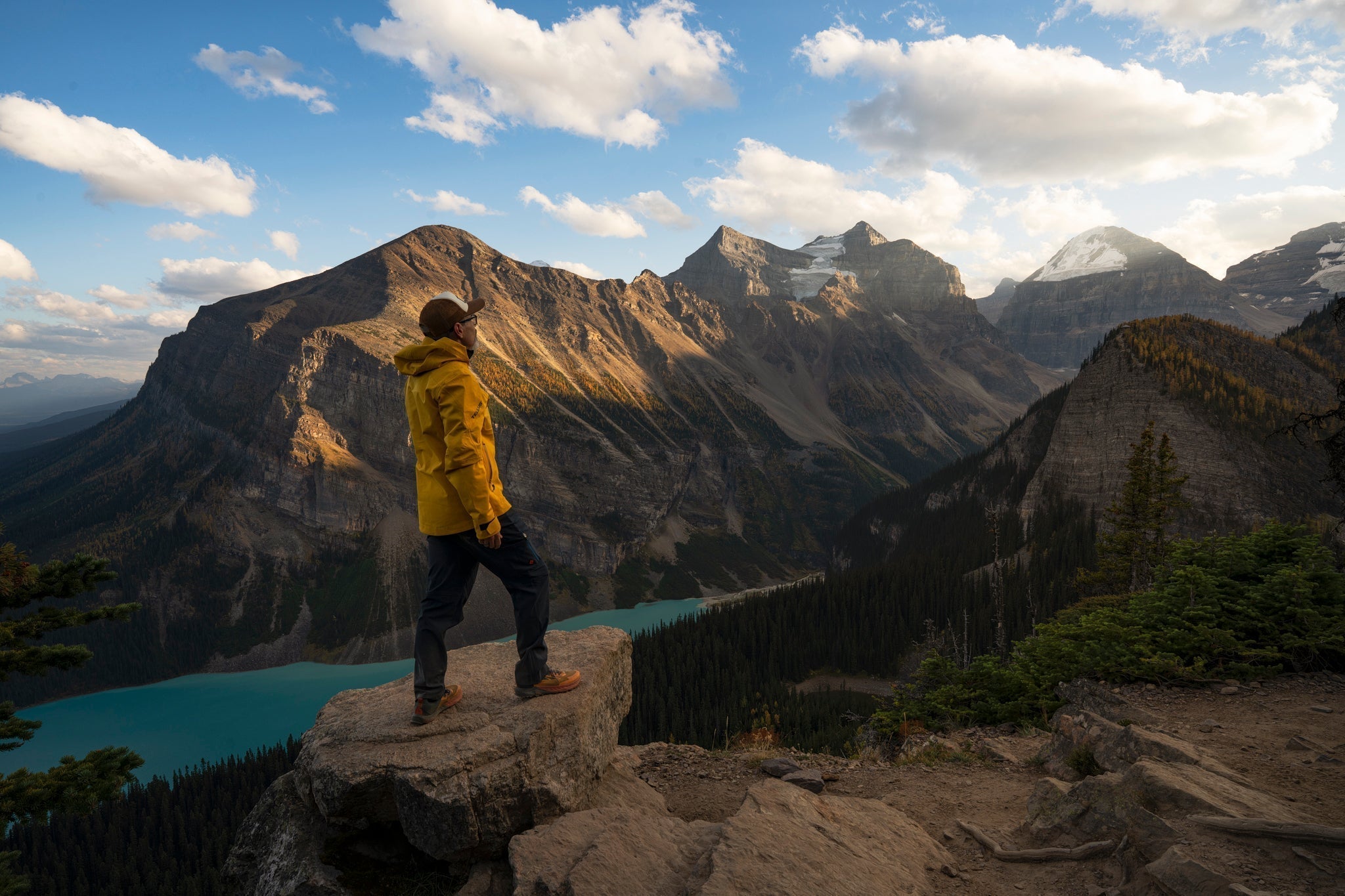 Brandt Ryder standing on peak looking out over the Canadian Rockies at dawn, wearing Tellus outdoor gear and a backpack, ready for an adventure with purpose.