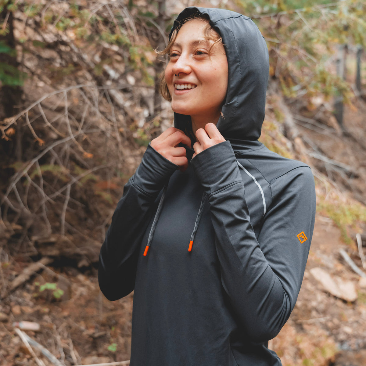Woman hiking wearing gray Horsetooth Performance Hoodie with hood up.