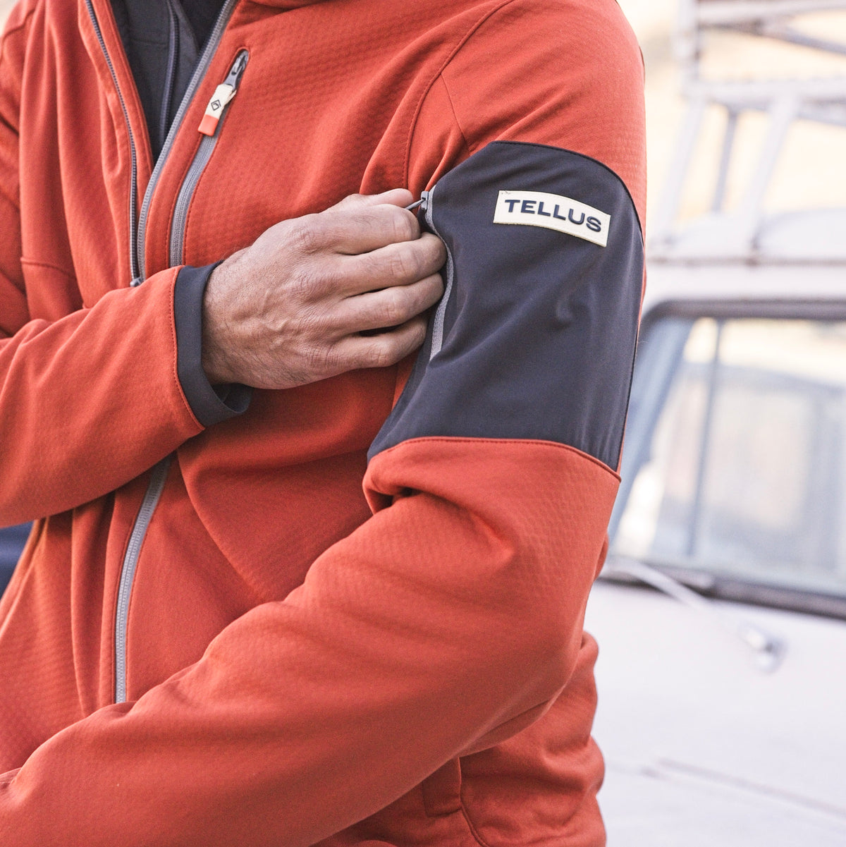 Man wearing an orange Front Range Fleece highlighting the zipper pocked on the sleeve.