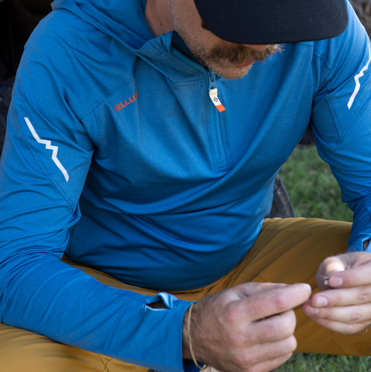 Man tying flies wearing blue Tellus Horsetooth Hoodie Quarter Zip.