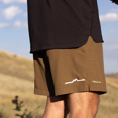 Man wearing brown Sunset Ridge PerformanceShorts and black top with foothills in background.